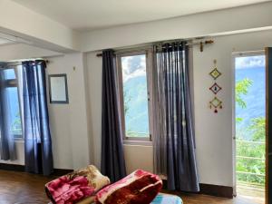 a living room with two windows and a couch at Petratos Homestay in Kalimpong