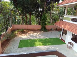 a small yard with a green lawn in front of a house at Dew Drops Inn kovalam in Kovalam