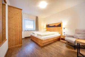 a bedroom with a bed and a couch and a chair at Apartments La Rives in Santa Cristina Gherdëina