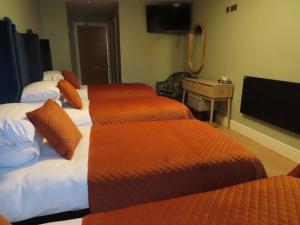 a hotel room with two beds and a television at The Stable Loft at Troysgate in Kilkenny +4 photos