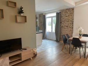 a living room with a television and a table with chairs at Appartement Le Pellerin 2ch et 2sdb in Le Pellerin