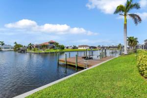 a dock on a lake with a palm tree at Sunsets At Tiki Terrace in Cape Coral