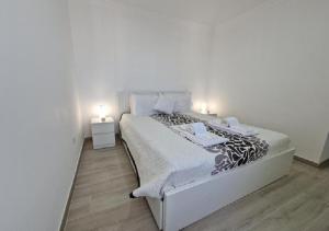 a white bedroom with a bed with two lights on it at Blue Sun Armação in Armação de Pêra
