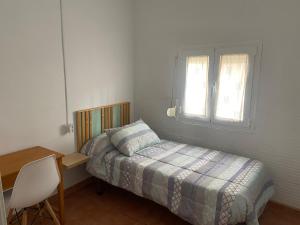 a bedroom with a bed and a desk and a window at Clau al castell apartament in Serra