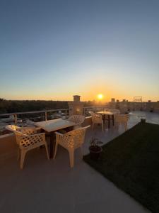 a patio with tables and chairs and the sunset at Siwa Star Rooms in Siwa