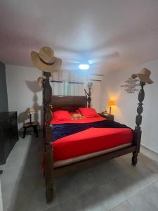 a bedroom with a bed with red sheets and a hat at LEN'HOUSE in Oyster Pond
