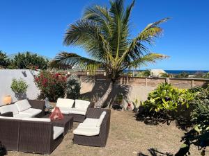 a patio with white couches and a palm tree at LEN'HOUSE in Oyster Pond