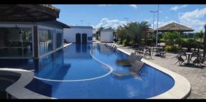 a large blue swimming pool with chairs and tables at Casa em clube in São José de Ribamar +21 photos