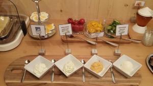 a table topped with bowls of cheese and fruit at Frühstückspension TROGER in Sankt Jakob in Defereggen