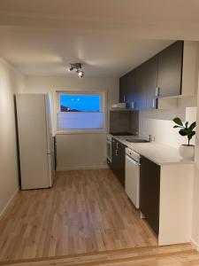 a kitchen with a white refrigerator and a window at Sentrumsnær sokkelleilighet in Svolvær