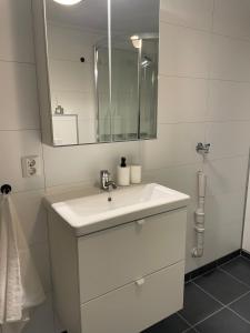 a white bathroom with a sink and a mirror at Sentrumsnær sokkelleilighet in Svolvær +18 photos