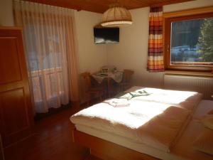 a bedroom with a bed and a table and a window at Frühstückspension TROGER in Sankt Jakob in Defereggen