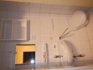 a white tiled bathroom with a toilet and a mirror at Frühstückspension TROGER in Sankt Jakob in Defereggen +99 photos