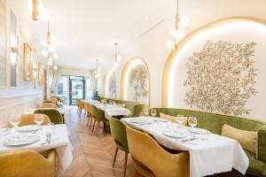 a restaurant with white tables and green chairs at Hotel Claridge Paris in Paris +43 photos