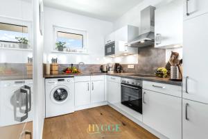 a white kitchen with a washer and dryer at Lodge 18 in Olpenitz +7 photos