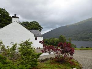 a white house with mountains in the background at Craigruie Farmhouse in Balquhidder