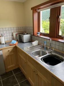 a kitchen with a sink and a microwave at Craigruie Farmhouse in Balquhidder +19 photos