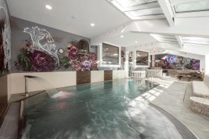 a swimming pool in a room with flowers on the wall at Hotel Zehnerkar & Hotel Obertauern in Obertauern