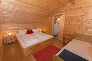 ein Schlafzimmer mit einem Bett in einer Holzhütte in der Unterkunft Grenerhof in Hopfgarten in Defereggen