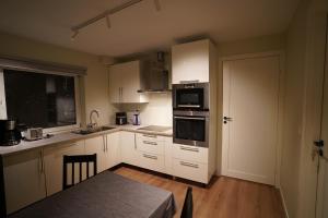 a kitchen with white cabinets and a table and a door at Cherry Rooms in Tromsø