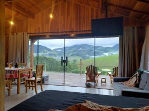 a living room with a large glass window with a view at Chalé Céu Estrelado in Paraisópolis