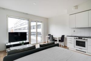 a white living room with a couch and a kitchen at Simple studio for two in Turku Center in Turku
