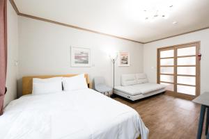 a bedroom with a large white bed and a chair at Suncheon Bay Ecology Pension in Suncheon