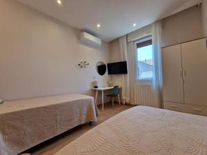 a bedroom with two beds and a table and a window at Dolce 2 bedrooms Apartment Milano 2mins to Rho Fiera & 25mins to Duomo Centre & 100m to Metro in Pero