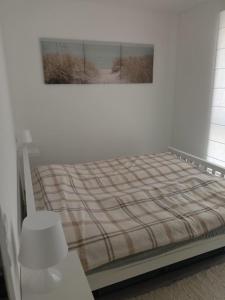 a bed in a white room with a picture on the wall at Przystań Nadole in Nadole