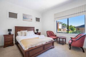 a bedroom with a bed and two chairs and a window at Welcome home Burwood in Burwood
