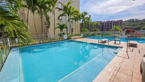 a large swimming pool with palm trees and a building at Capriella, Serena Del Mar in Cartagena de Indias