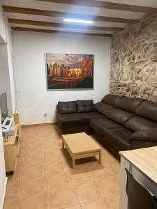 a living room with a leather couch and a table at Clau al castell apartament in Serra