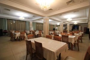 a restaurant with white tables and chairs and chandeliers at Алма Ата in Borovoye