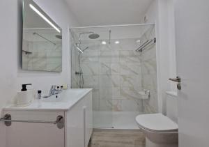 a white bathroom with a shower and a toilet at Blue Sun Armação in Armação de Pêra +16 photos
