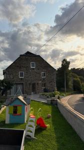 a house with a yard with play equipment in the grass at Famenne Escape in Marche-en-Famenne