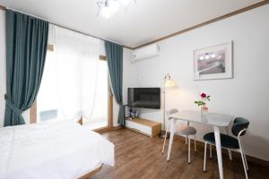 a bedroom with a bed and a table and a television at Suncheon Bay Ecology Pension in Suncheon