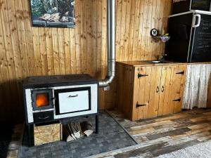 a stove in a room with a wooden wall at Tiny House at Sedliacky Dvor - Brezno in Brezno