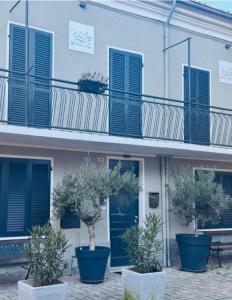 a building with blue doors and potted trees in front of it at Bottega del Sogno in Alice Bel Colle