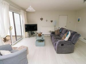 a living room with a couch and a tv at Sunset Sands in Deganwy