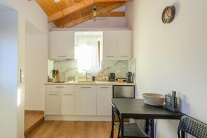 a kitchen with white cabinets and a table at Voidοkilia rooms in Petrochori +20 photos
