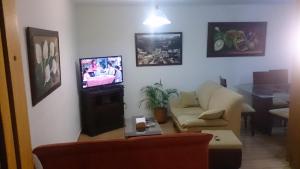 ein Wohnzimmer mit einem Sofa und einem TV in der Unterkunft Apartamento Los Delfines del Caribe in Cartagena de Indias