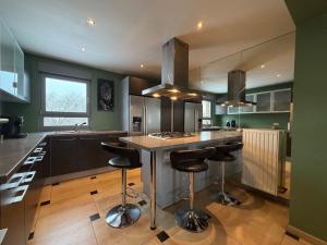 a kitchen with green walls and a island with bar stools at Cosy Duplex pour 4 personnes à Soignies in Soignies