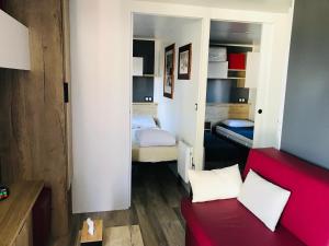a small room with two beds and a red couch at Chalet du Mont-Saint-Michel in Saint-Jean-le-Thomas