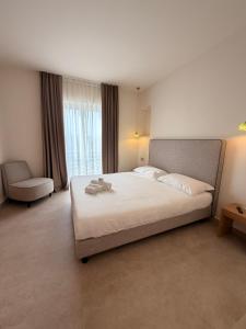 a bedroom with a large white bed and a chair at Ab aparthotel in Gizzeria