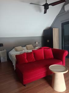 a red couch in a living room with a bed at Villa Naiya in Saint-Paul