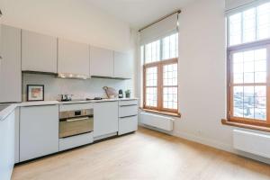 an empty kitchen with white cabinets and windows at Apartment near Antwerp Cathedral in Antwerp +14 photos