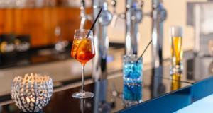 Ein Getränk in einem Glas auf einer Theke mit zwei Vasen. in der Unterkunft PLAZA INN Wels in Wels + 48 Fotos