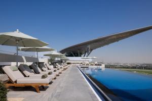 a row of chairs and umbrellas next to a swimming pool at The Meydan Hotel Dubai in Dubai