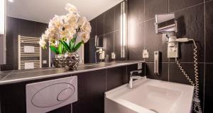 ein Badezimmer mit Waschbecken und einer Blumenvase in der Unterkunft PLAZA INN Wels in Wels