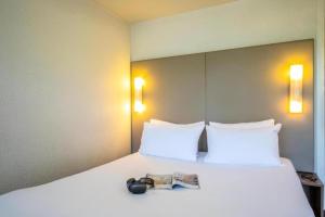 a bedroom with a bed with a magazine on it at Campanile Saint Quentin in Saint-Quentin